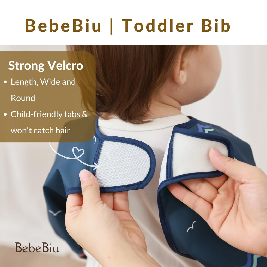 BebeBiu Long Sleeve Baby Bib, Waterproof Fabric, Full Coverage with Catch-All Pocket, Baby Smock Bib, Adjustable Sleeves Toddler bib for Ages 6-24 Months (Bows Blush, Small 6-24 Months)